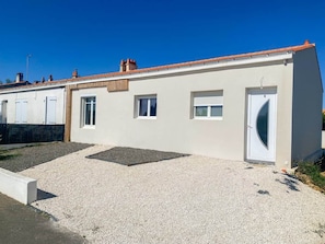 A single-story building with a flat roof, a door with a semi-circular glass panel, and a gravel driveway. - La Lagune - Bright House with Garden in Les Sables-d'Olonne (Les Sables-d'Olonne)