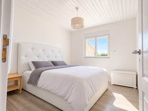 A bedroom with a bed, bedside table, and a window.