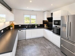 A modern kitchen with white cabinets, black countertops, a stainless steel refrigerator, and a built-in oven. - La Lagune - Bright House with Garden in Les Sables-d'Olonne (Les Sables-d'Olonne)