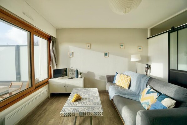 A modern living room with a sofa, a coffee table, and a television on a white cabinet.