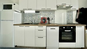 A kitchen with white cabinets, a microwave, a coffee maker, and a dishwasher.