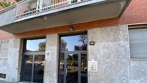 A building entrance with a glass door, a metal balcony, and a parking sign. - Fornari 48 Comfortable Flat (Milan)