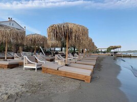Una playa con tumbonas y sombrillas de paja.