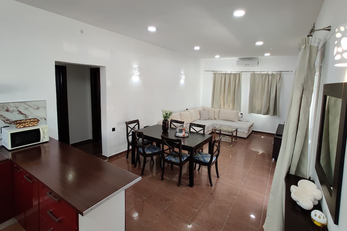 A modern living room with a dining area, a sofa, and a TV.