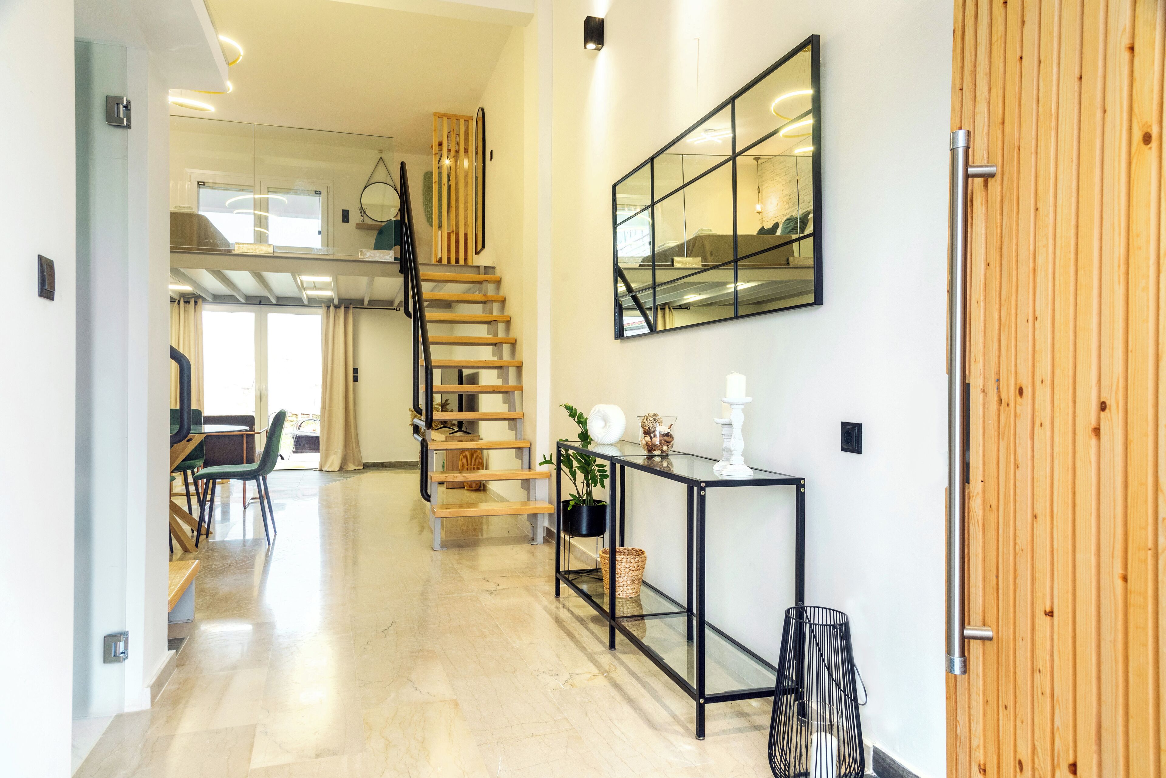 A modern interior with a staircase, a dining area, and a large mirror.