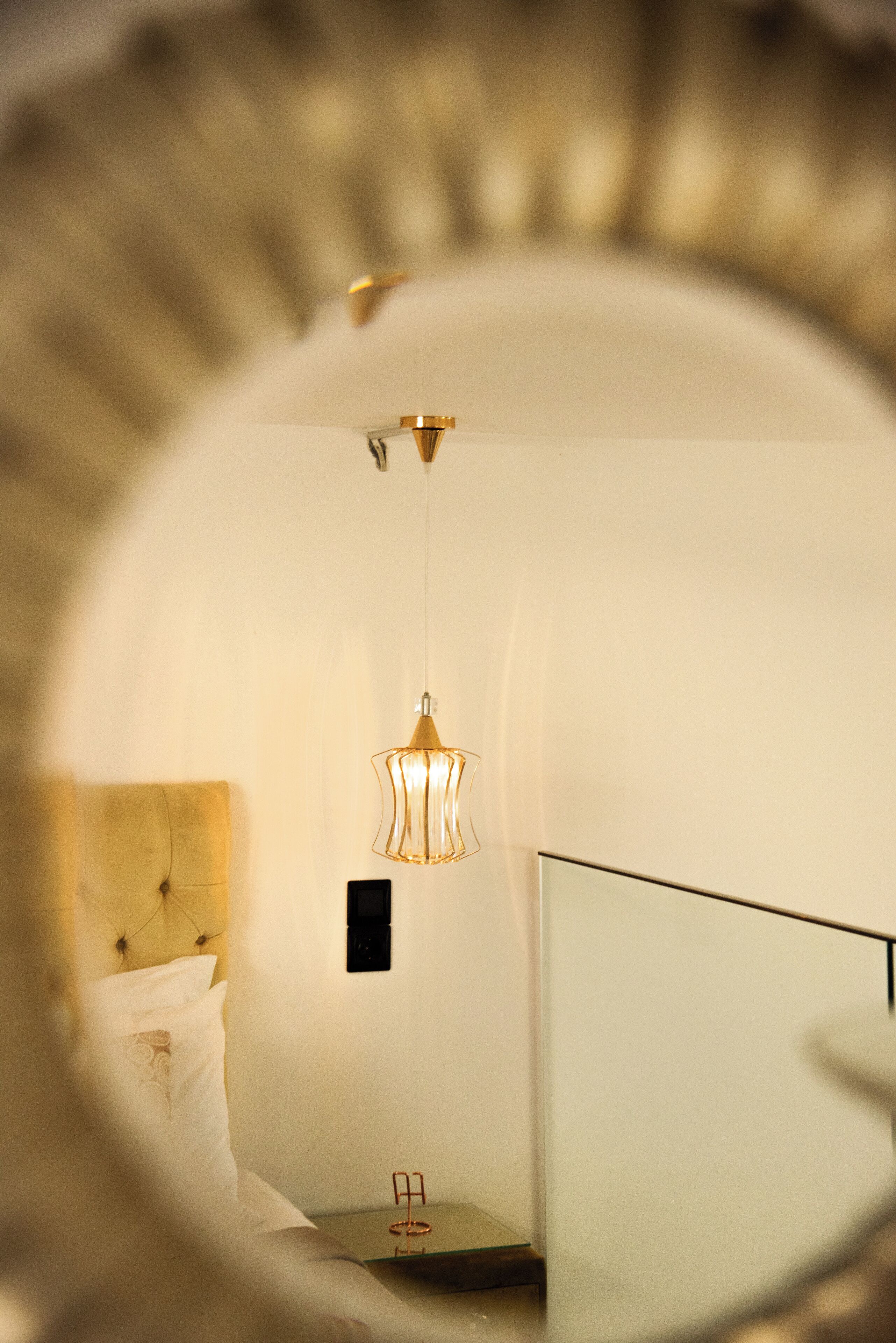 A modern bedroom with a bed, a bedside table, and a hanging light fixture.