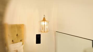 A modern bedroom with a bed, a bedside table, and a hanging light fixture.