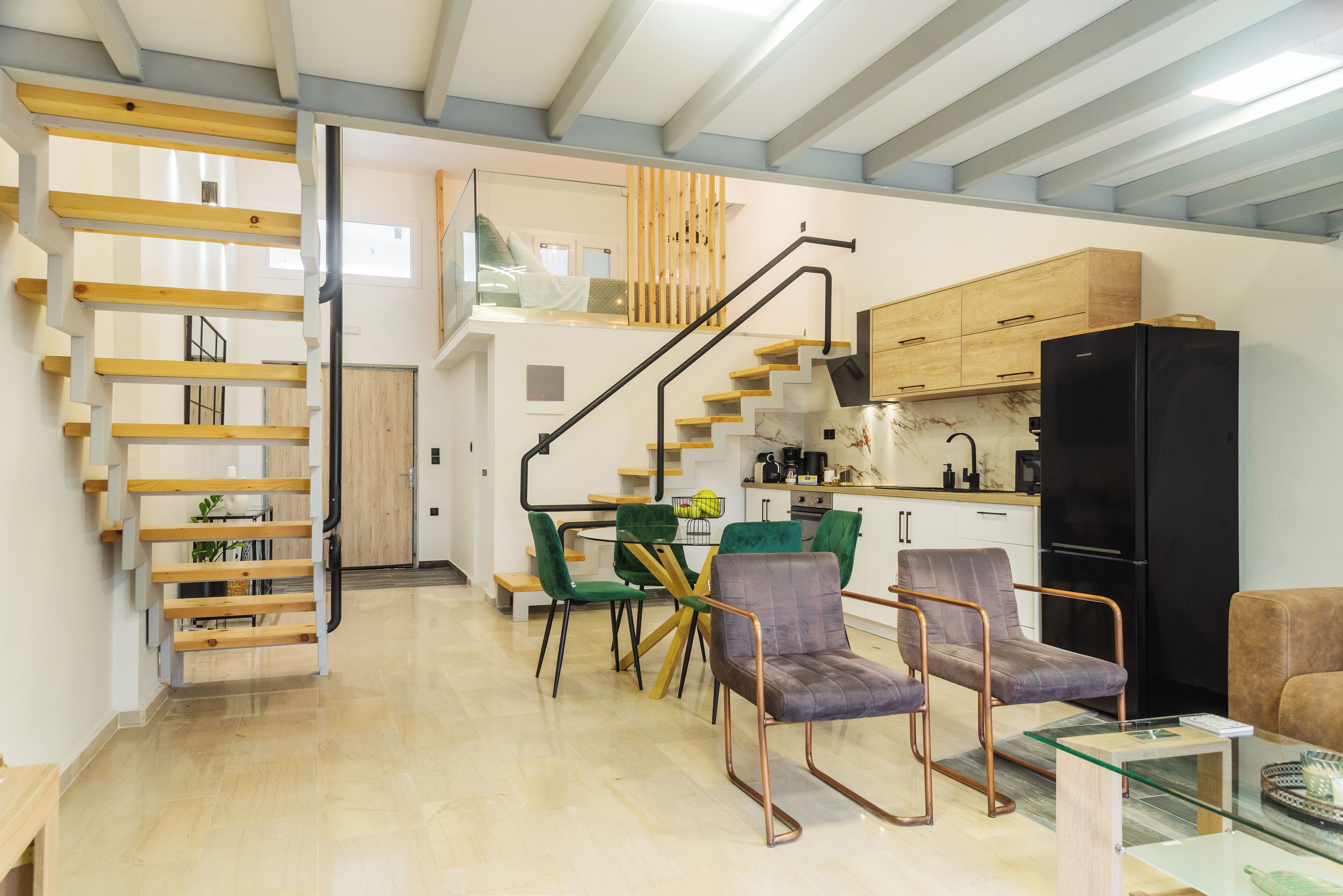A modern kitchen with a black refrigerator, wooden cabinets, and a dining area with green chairs.