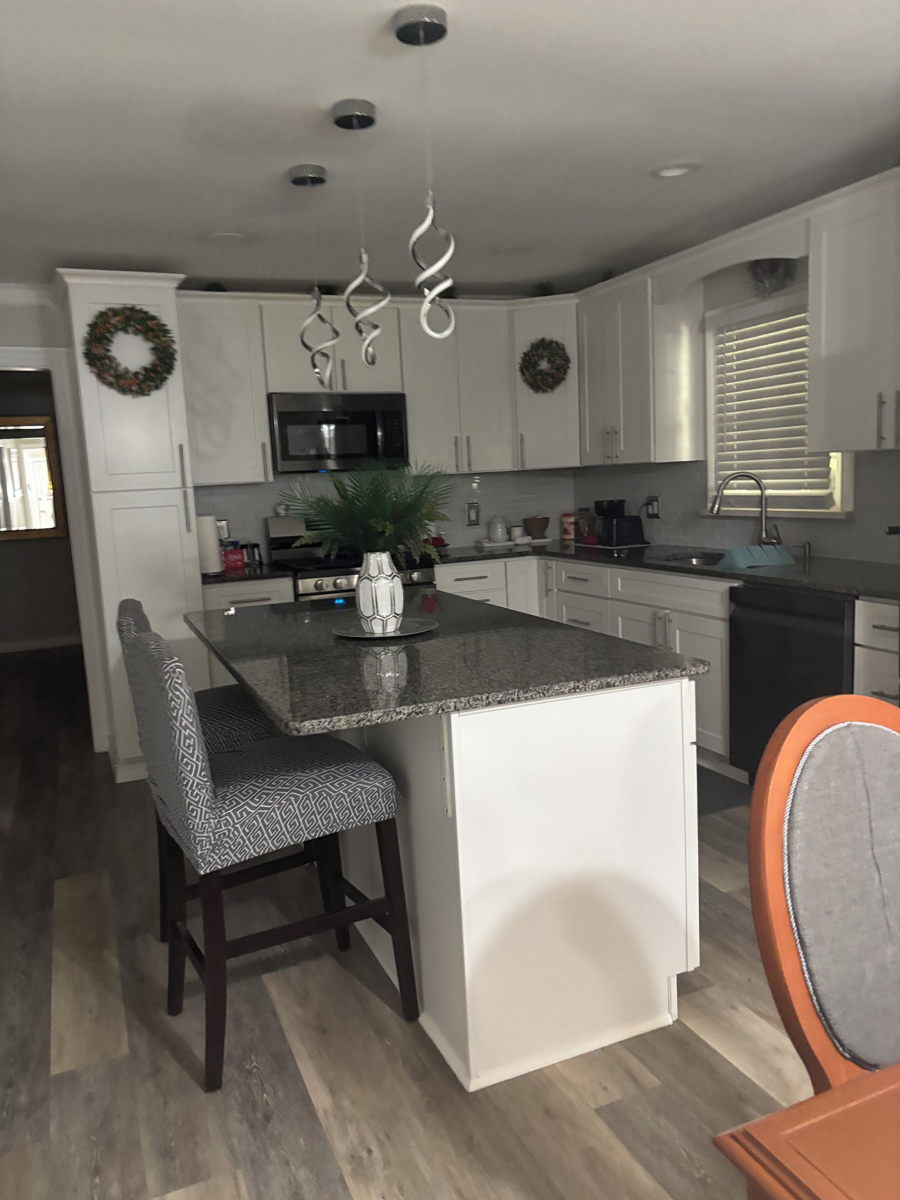 A modern kitchen with white cabinetry, a central island, and a built-in microwave.