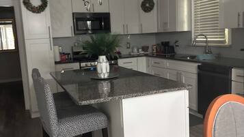 A modern kitchen with white cabinetry, a central island, and a built-in microwave.