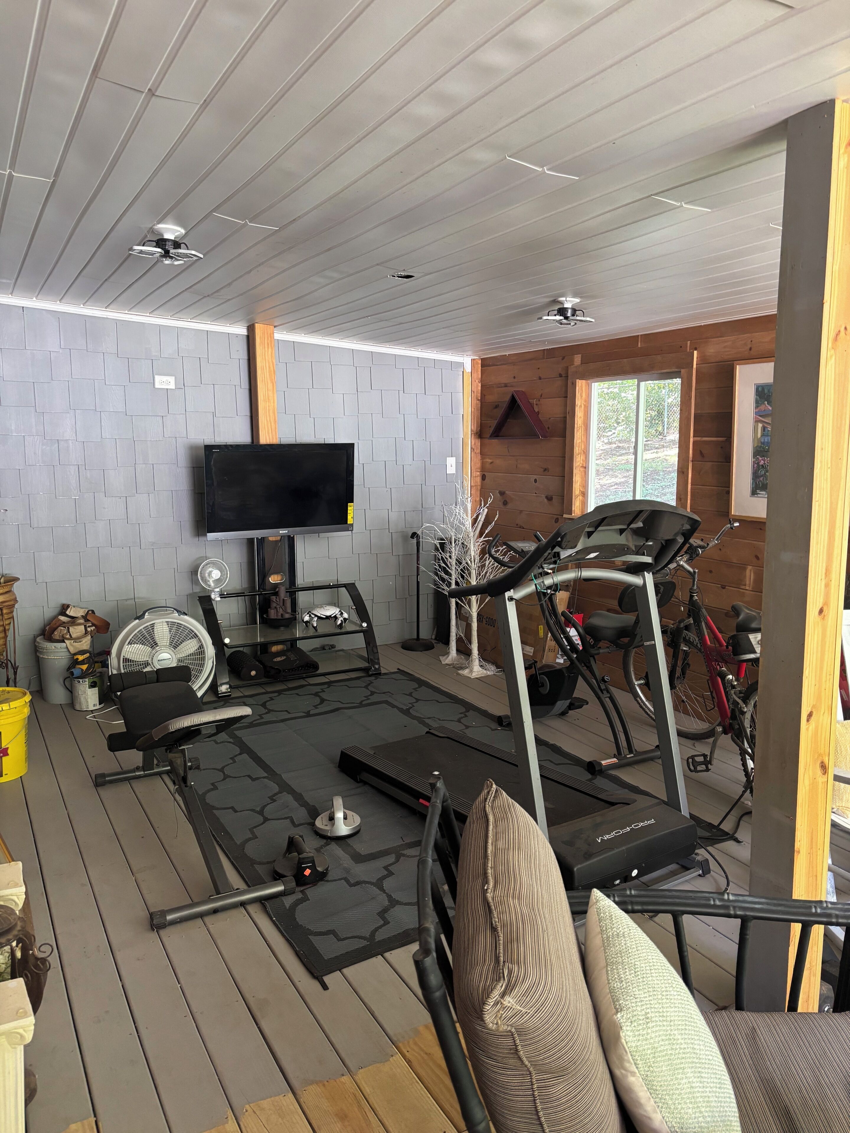 A gym area with exercise equipment, a television, and a wooden interior.