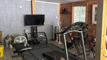A gym area with exercise equipment, a television, and a wooden interior.