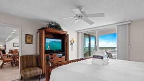 Une chambre d’hôtel comprenant un lit, une télévision, une armoire en bois, une chaise et un balcon avec vue.