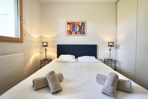 A hotel room with a large bed, two bedside lamps, a headboard, and a colorful abstract painting on the wall.
