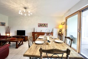 A dining area with a wooden table set for four, a television, and a fireplace.
