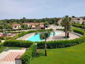 A pool surrounded by a well-maintained garden, with a palm tree and a checkered patio area. - Residence San Bull (Bernalda)