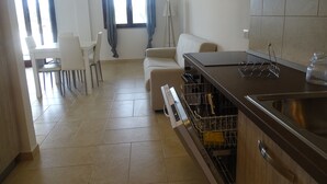 Uma cozinha moderna com lava-louças, uma sala de jantar com cadeiras e um sofá.