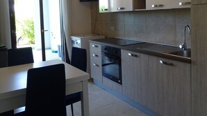 Uma cozinha moderna com área de jantar, com forno embutido, pia e televisão na parede.