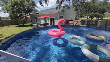 Una piscina con flotadores inflables de aros y un flamenco.