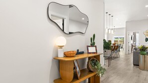 A modern interior with a wooden console table, a mirror, a lamp, and a cactus. - Charleston-themed House for 10! (Goose Creek)