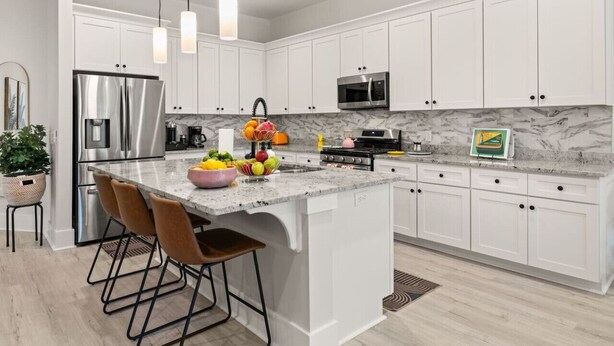 A modern kitchen with white cabinets, stainless steel appliances, and a marble countertop. - Charleston-themed House for 10! (Goose Creek)