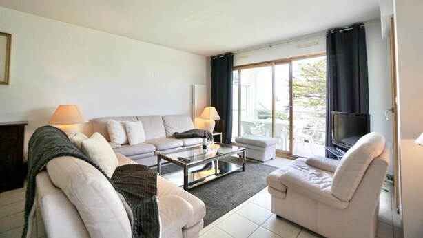 Een moderne woonkamer met een bank, fauteuils, een salontafel en een televisie.