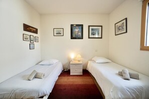 Una stanza con due letti singoli, un comodino con una lampada e quadri appesi alle pareti.