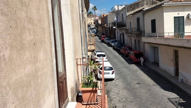 A narrow street lined with parked cars and buildings with balconies. - Casa Vacanze Relax Etna With Stunning Natural Beauty View (Giarre)