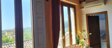 A room with large windows, a balcony, and a view of the landscape.