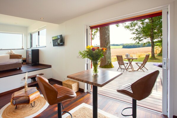A modern living room with a wooden table, two brown chairs, a sofa, and a TV.