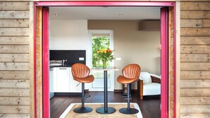 Un interior moderno con fachada de madera, una zona de cocina y un espacio de descanso con dos sillas y una mesa.