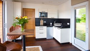 Una cocina moderna con armarios blancos, una mesa de comedor de madera y un jarrón de flores.