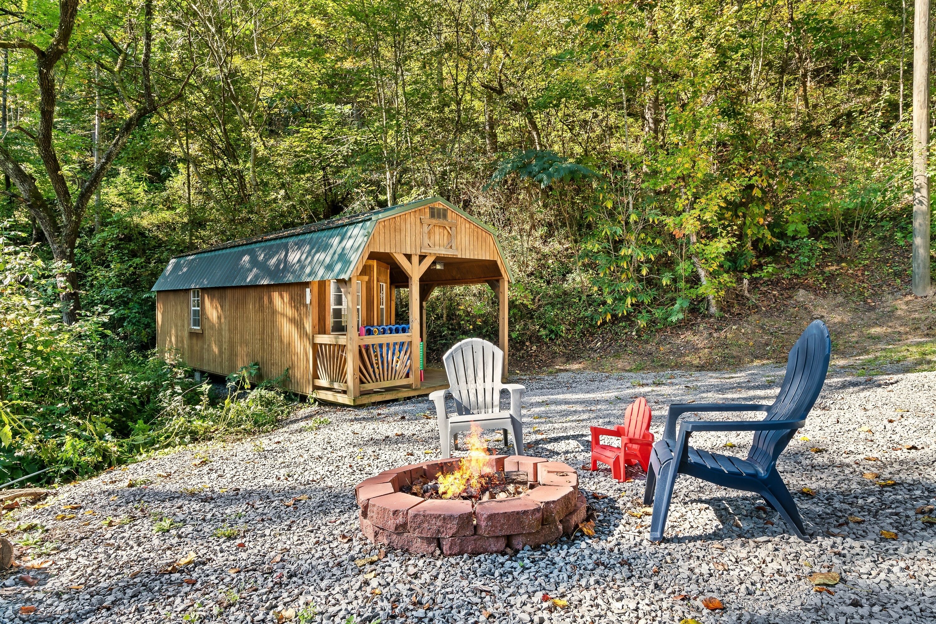Une cabane en bois avec une véranda, un foyer et deux fauteuils Adirondack.