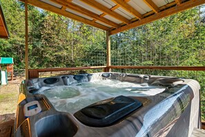 Ein Whirlpool mit einer Holterrasse und Blick auf einen Wald.
