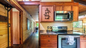 A wooden interior with a kitchen area featuring a microwave, oven, and stove.