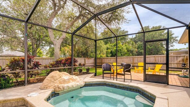 Un jardin avec un jacuzzi, du mobilier d’extérieur et une clôture en bois.