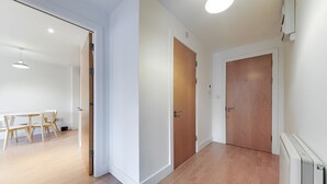 A hallway with wooden flooring, white walls, and two wooden doors. There is a table and chairs in the background. - Still Life Clerkenwell Deluxe (London)