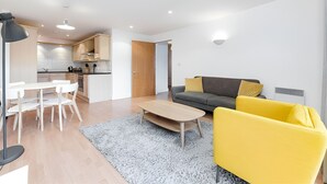 A modern apartment with a dining area, a sofa, and a kitchen in the background. - Still Life Clerkenwell Deluxe (London)