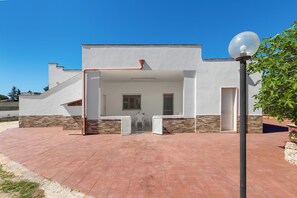 En moderne bygning med hvid facade, detaljer i sten og en anlagt patio.