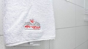 A white towel with a logo and text on a tiled wall.