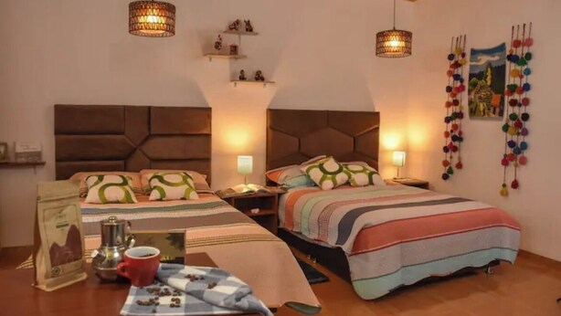 A cozy hotel room with two beds, a coffee table, and decorative wall hangings.