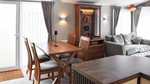 A modern living room with a wooden dining table, grey sofa, and a cabinet with decorative items. - 2 bedroom accommodation in Moota, near Cockermouth (Moota, near Cockermouth)