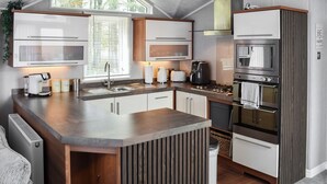 A modern kitchen with a central island, built-in appliances, and a large window providing natural light. - 2 bedroom accommodation in Moota, near Cockermouth (Moota, near Cockermouth)