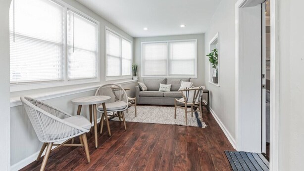 A cozy living room with a grey sofa, a white chair, a small round table, and a potted plant.