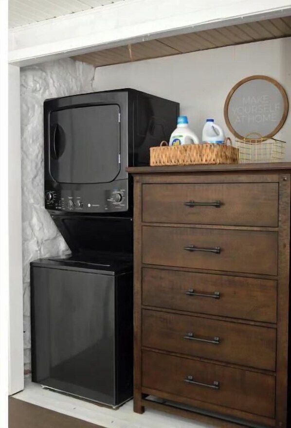 Une cuisine de taille réduite, avec un réfrigérateur noir, un four à micro-ondes et un meuble en bois doté de tiroirs.