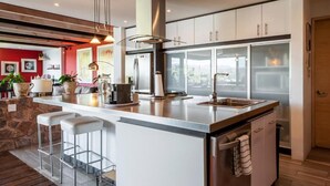 Une cuisine moderne dotée d’un îlot central, d’appareils électroménagers en acier inoxydable et d’une grande fenêtre offrant une vue sur la ville.