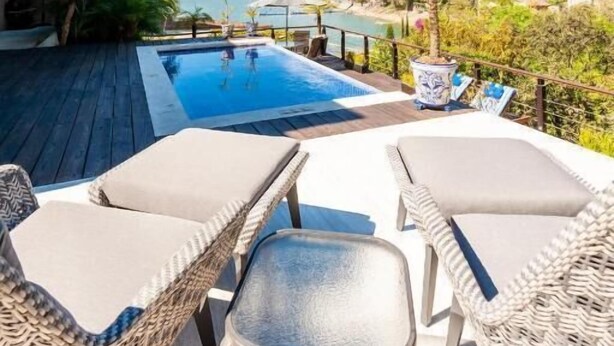 Une piscine sur le toit, dotée de chaises longues et offrant une vue sur la mer.