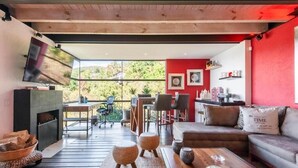 Un salon moderne avec une cheminée, un canapé, une table basse et un téléviseur fixé au mur.