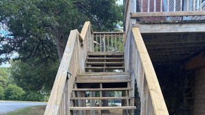 A wooden staircase with a handrail, leading up to a building entrance. - The Backyard Bungalow (Batesville)