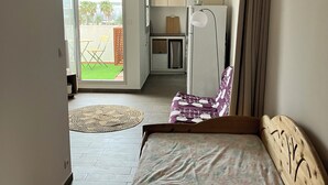 Een slaapkamer met een bed, een kitchenette en uitzicht op de omgeving.